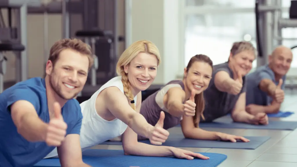Een rustige fitnessstudio met zachte belichting, waar een trainer een klant begeleidt bij basis oefeningen zoals squats of lunges, in een kalme en ondersteunende omgeving.